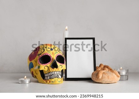Bread of the dead with candles, frame and painted skull on white table. Celebration of Mexico's Day of the Dead (El Dia de Muertos)
