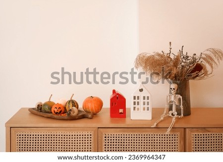Vase with pampas grass, candle holders and Halloween decor on drawers in room