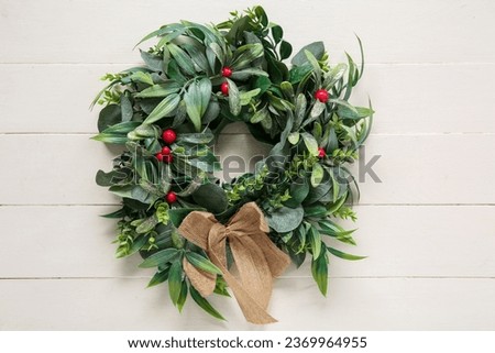 Beautiful mistletoe wreath on white wooden background