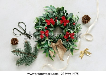 Beautiful mistletoe wreath, scissors, ribbon, bow, fir branch and pine cones on white background