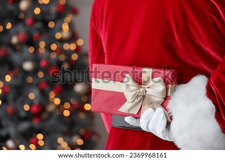 Santa Claus with gift box at home on Christmas eve, back view