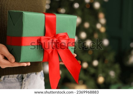 Woman holding gift box at home on Christmas eve, closeup