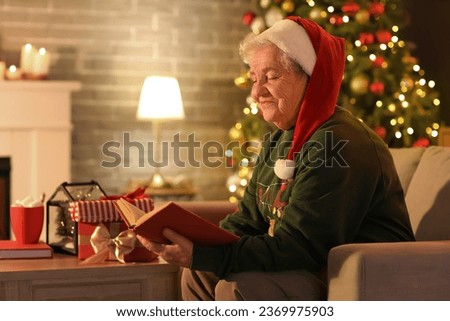 Senior woman in Santa hat reading book at home on Christmas eve