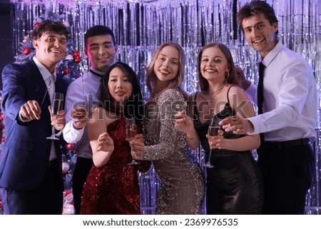 Group of young people with champagne and sparklers at Christmas party