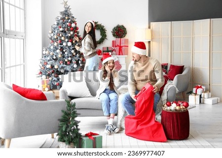 Young man with bag of Christmas gifts and his family at home