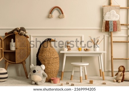 Warm and cozy kids room interior with white desk, stool, animal wicker basket, rattan sideboard, stylish toys, plush monkey, koala, wooden blockers, pouf and personal accessories. Home decor. Template