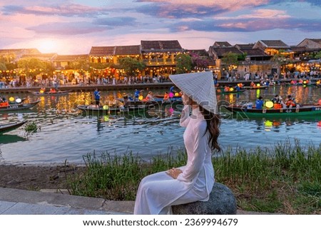 Vietnamese women in national costumes at the ancient town. Vietnam. Hoi An. Street view with traditional boats and lifestyle on the background of the ancient town.	 Royalty-Free Stock Photo #2369994679