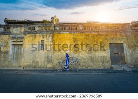 Vietnamese girls in national costumes and ancient bicycle at the old town of Hoi An, Vietnam. with a beautiful and unique architecture. Royalty-Free Stock Photo #2369996589