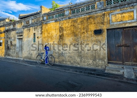 Vietnamese girls in national costumes and ancient bicycle at the old town of Hoi An, Vietnam. with a beautiful and unique architecture. Royalty-Free Stock Photo #2369999543