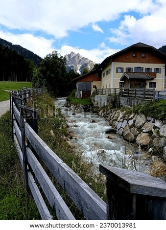 In one part of the Braies valley the stream descends rapidly alongside the houses, with Picco Vallandro in the background Royalty-Free Stock Photo #2370013981