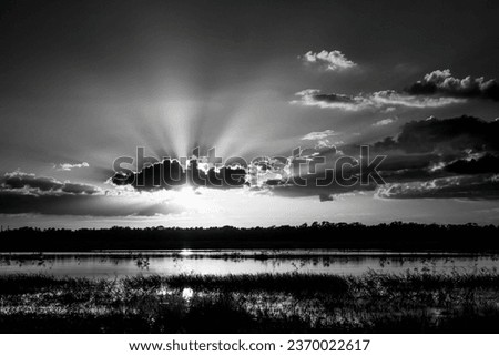 INfrared Red black and white image of sun with sun rays in blue sky with clouds at sunset over Myakka River State Park in Sarasota Florida USA