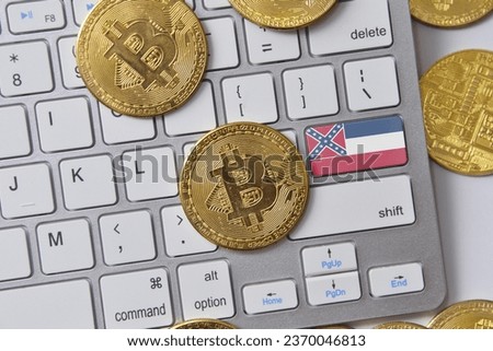 flag of mississippi state on the keyboard with bitcoin coins on a grey background. concept
