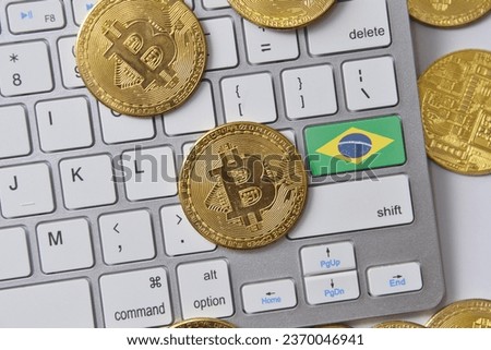 national flag of brazil on the keyboard with bitcoin coins on a grey background. concept Royalty-Free Stock Photo #2370046941