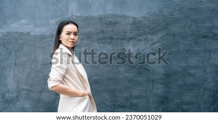 Portrait of successful business asian woman in grey suit with smile isolated over blue background. Business stock photo.