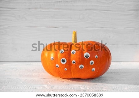 Pumpkin with Eyes for Halloween. Humor, Creative. One Big Orange Pumpkin with Many Eyes. Single Spooky Halloween Pumpkin, Jack O Lantern with Evil Face. White Wooden Textured Background. Front View