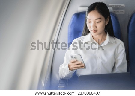 Traveling and technology. young business woman working on laptop computer and smartphone while sitting in airplane.