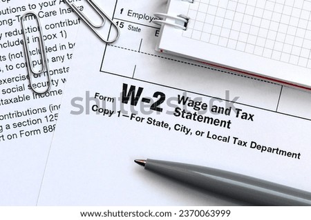 The pen and notebook on the tax form W-2 Wage and Tax Statement. The time to pay taxes Royalty-Free Stock Photo #2370063999