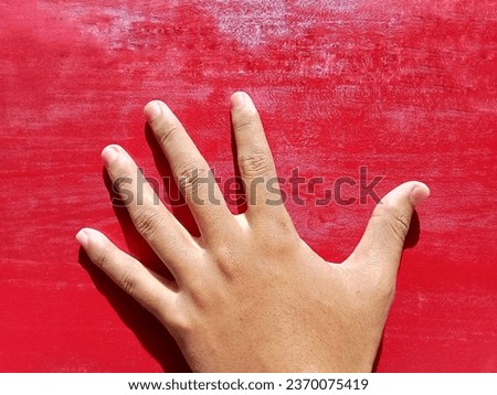 Human hand fingers on red wooden background.