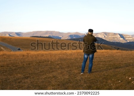 An adult male photographing a mountain landscape with a long lens. Copy space.                               