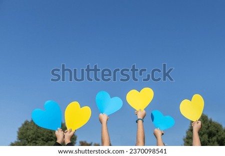children's hands hold yellow and blue hearts above their heads against the blue sky on a sunny day. concept of patriotism, unity, support, peace for Ukraine. I am proud to be Ukrainian. Stop the war