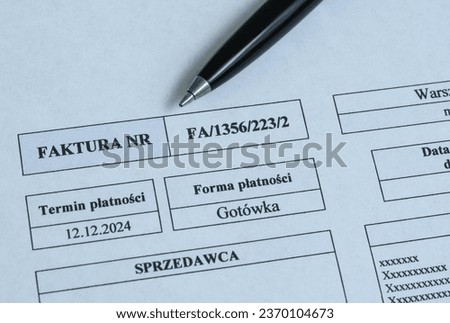 Paper invoice and pen lying on the desk in the company, translation of the inscriptions on the paper "payment method: cash, payment term, invoice, seller",