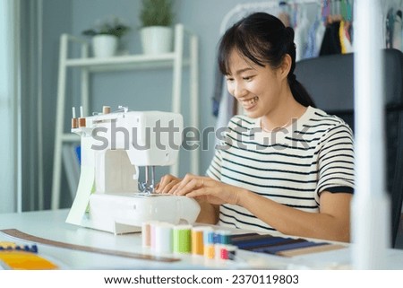 Happy beautiful Asian young woman working in the fashion design studio, professional female fashion designer portrait in design studio.