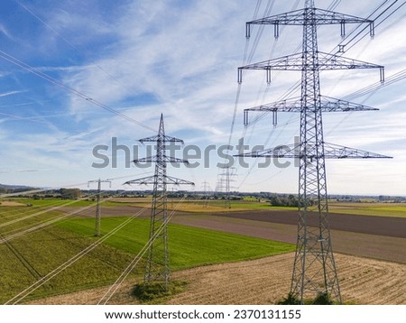 Aerial view of a row of high voltage pylons with many power lines in rural area to the horizon Royalty-Free Stock Photo #2370131155