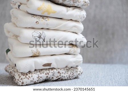 stack of clean baby clothes with a pattern on grey background. Neatly folded clothes