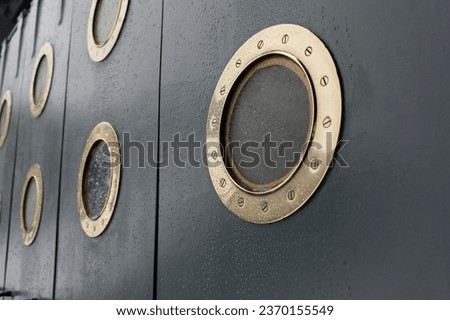 round portholes, shiny bronze, old ship, raindrops, water splashes, storm Royalty-Free Stock Photo #2370155549