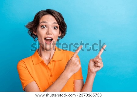 Photo of charming impressed girl dressed orange polo showing two fingers empty space isolated blue color background