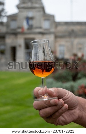 Tasting of Cognac strong alcohol drink in Cognac region, Charente with view on ols houses and streets of Cognac town on background, France is autumn