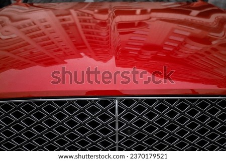 Front view of a modern luxury car in bright red. Pictured: part of the grille and hood. New car sales, service and spare parts. Concept