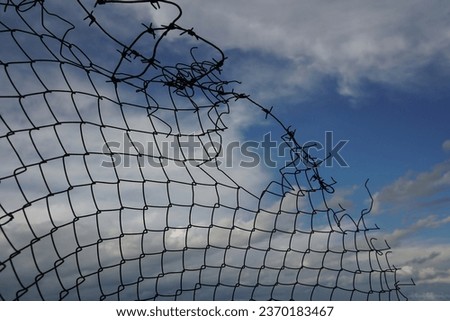 chain link fence with blue sky and clouds. wire fence. Chain link fence see sky. Opening in metallic fence. blue sky. Challenge. breakthrough concept.                                                  