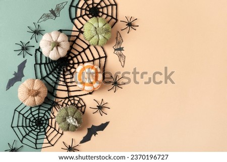 Halloween greeting card mockup with copy space. Halloween decorations, spiders, bats, knitted webs, pumpkins on green and beige background. Happy Halloween holiday concept. Flat lay, top view
