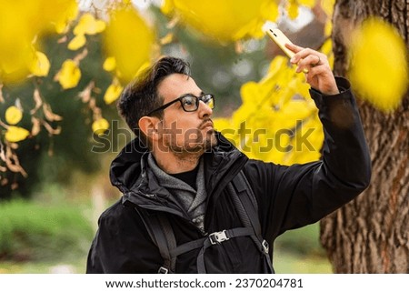 Smiling man taking a picture of the autumn landscape.