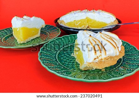 Lemon Meringue Pie being sliced and served on green plates against red background.