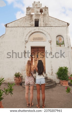 Italian churches hold secrets beyond this life. Full length shot of two unrecognisable women standing together and using their cellphone to take pictures of a church.