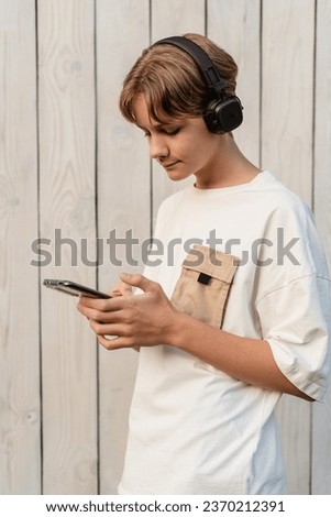 Teen boy looking on smartphones and chatting online outdoor, talking and typing on phone, reading a message on phone, kid and smartphone, browsing social media, internet business