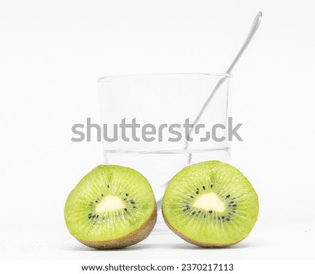 Explore the vibrant world of healthy eating with our stunning photograph of two ripe kiwis in sharp focus, set against a beautifully blurred background featuring a glass of water and a fork.