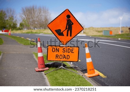 Works on side road sign surrounded by red cones at Gulf Harbour Drive