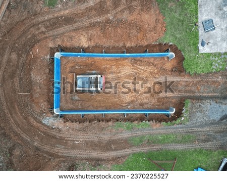 Skid steer digging the deep end of a pool under construction Royalty-Free Stock Photo #2370225527
