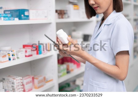 Asian professional female pharmacist using tablet to check drug list Pharmacist checking stock in pharmacy for health medicine in technology pharmacy looking at camera smiling