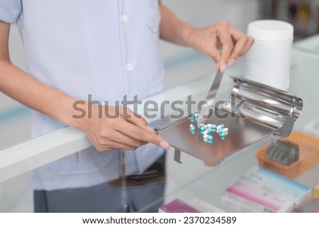 Asian professional female pharmacist standing with arms crossed looking at camera charming smile pointing hand to pill bottle health care products in pharmacies Close-up and wide-angle shots