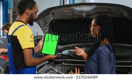 African american serviceman using green screen laptop to show woman damaged parts found in her car. Expert using isolated device to help client visualize repairments that need to be done to vehicle