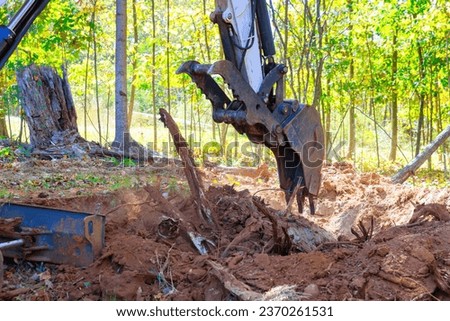 Using excavator, worker uproots trees in preparation for construction of new building Royalty-Free Stock Photo #2370261531