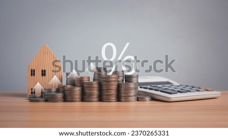 Model wooden house, calculator and coins lined up on wooden floor on white background. Concepts of mortgage, loand, transfer, finance, savings and investment. Real estate tax concepts.