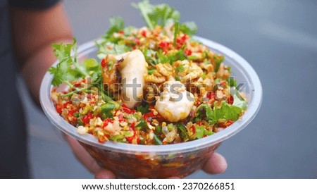 Picture of grilled squid in Thai style on holding hand, eat with spicy seafood dipping sauce. Photos of street food in Thailand