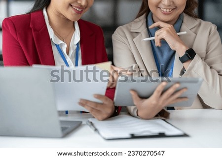 Two Asian businesswomen discuss working on a new project idea presentation. Calculate marketing plans and investments real estate tax office
