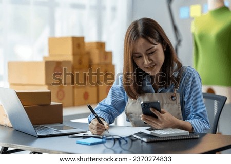Small business start-up, SME owner, female entrepreneur working on packaging parcels. Receipt and check orders online to prepare boxes for sale to customers, online SME business concept.