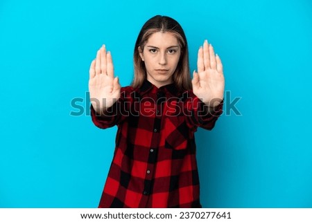 Young caucasian woman isolated on blue background making stop gesture and disappointed